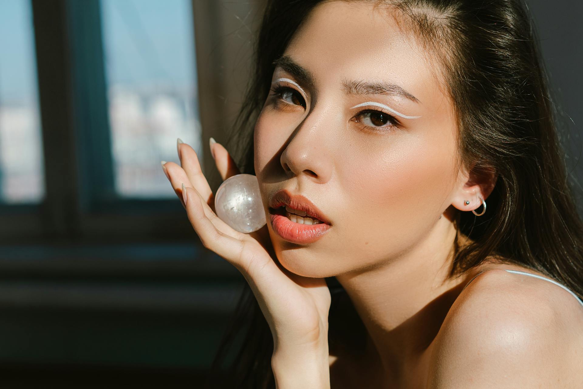 A Beautiful Woman Holding a Moonstone while Looking at the Camera