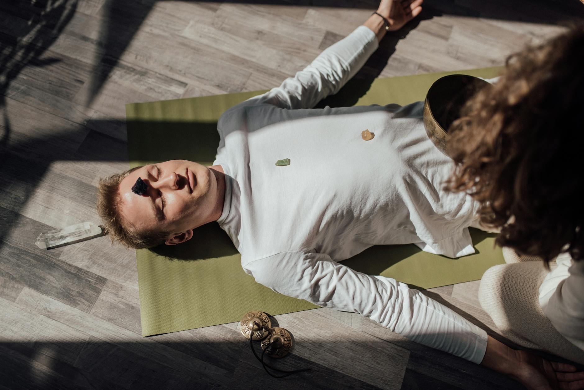 man lying down on floor with healing quartz stone on forehead