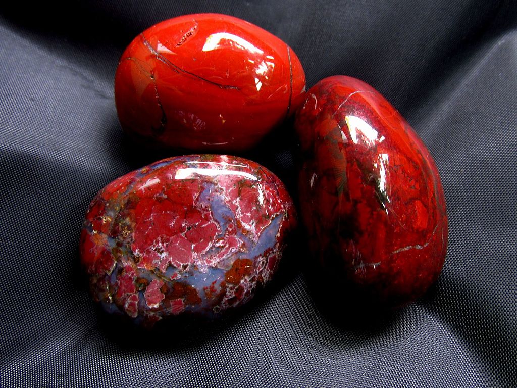 A group of three polished red jasper stones